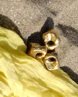 Anillo dorado con forma irregular y un agujero en el centro.