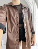 Sobrecamisa color chocolate de cuero sintético con cuello clásico, cierre frontal con botones a presión plateados, bolsillo de parche en el pecho y puños con botón.