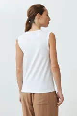 Musculosa de algodón color rojo, con cuello redondo, corte sin mangas y detalle de botones decorativos en los hombros.