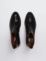 Botineta de cuero negro con textura de reptil, taco cuadrado y cierre trasero.
