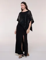Vestido largo azul marino de seda fría, compuesto por una falda recta con tajo frontal y una capa superior superpuesta de encaje con lentejuelas bordadas, escote a la base y mangas tres cuartos acampanadas.
