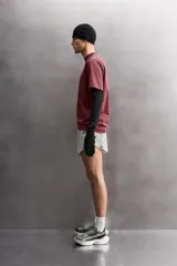 Camiseta de entrenamiento de ajuste relajado, color vino tinto, confeccionada en tejido de peso medio con mezcla de algodón. Presenta cuello redondo con acabado en vivo doble y manga corta.