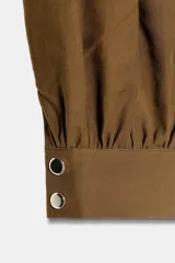 Pantalón de tiro medio con diseño bombacho, frunces delanteros y pierna abullonada con puños ajustados. Incluye bolsillos frontales y un cinturón decorativo con cadena metálica.