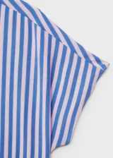 Camisa celeste con rayas verticales blancas, de corte recto, cuello camisero y mangas cortas murciélago. Cierre frontal con dos botones.