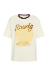 Remera de algodón color beige con cuello redondo en contraste marrón. Presenta mangas cortas y un estampado frontal con temática western que incluye letras y una ilustración central.