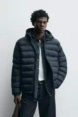 Campera puffer acolchada de corte regular fit en color negro, confeccionada en tejido técnico repelente al agua. Presenta cuello subido con capucha, cierre frontal de cremallera, mangas largas con puños elásticos y bolsillos laterales de vivo.