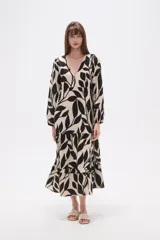 Vestido midi holgado con estampado de hojas en blanco y negro, cuello en V, mangas largas con elástico en los puños y falda con volados.