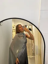 Vestido largo de tafeta con brillo, color verde, de corte al cuerpo y escote asimétrico de un solo hombro. Incluye una pieza de seda liviana drapeada sobre el hombro opuesto.