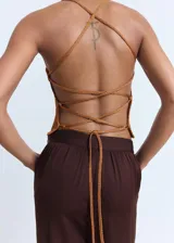 Top de punto con acabado de lúrex en color bronce, de diseño entallado, cuello escotado y tirantes finos que se cruzan en la espalda.