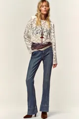 Top de encaje negro con cuello redondo, manga larga y hombreras incorporadas. Presenta un diseño de corte recto y cierre posterior.