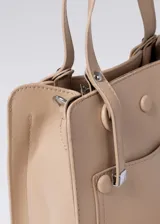 Cartera color beige de cuero sintético, con doble asa corta y correa larga extraíble con estampado de letras en dorado.