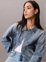 Campera de denim Calvin Klein en tono azul lavado, con corte relajado, cierre frontal con botones metálicos y doble bolsillo frontal con solapa.