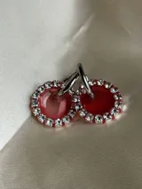 Aros colgantes con forma circular, hechos de resina color lila y borde de strass plateado. El aro es de acero quirúrgico plateado.