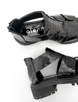 Sandalias negras de cuero con textura escamada, corte asimétrico y suela track.