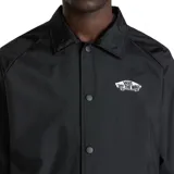 Campera negra de corte clásico con cuello camisero, cierre frontal con botones a presión, puños elásticos y cordón ajustable en la cintura. Presenta el logo de Vans "Off The Wall" estampado en el pecho.