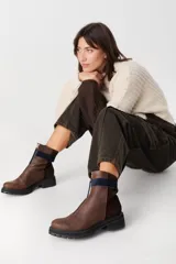 Bota corta de cuero color marrón con cierre frontal, suela track negra y paneles laterales en gamuza de un tono más oscuro.