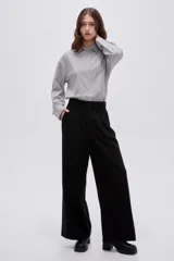 Pantalón negro de tiro alto, confeccionado en viscosa, de corte holgado y pernera ancha, con bolsillos laterales.