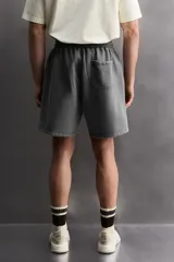 Short tipo jogger de algodón con interior afelpado, cintura elástica ajustable con cordón, bolsillos frontales y bolsillo trasero. Presenta un efecto lavado y estampado gráfico a contraste en el frente.