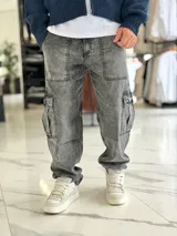 Pantalón cargo de jean azul claro, con bolsillos laterales tipo cargo en las piernas y bolsillos frontales aplicados, de corte ancho y holgado.