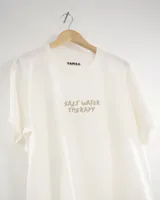 Remera oversize de algodón color blanco hueso, con estampado frontal que dice "SALT WATER THERAPY" en color beige.