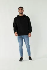 Buzo de felpa negro con capucha, cordones ajustables y bolsillo tipo canguro. Tiene puños y cintura acanalados, y logo en grifa de plástico.