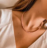 Collar corto de cuentas pequeñas color rosa viejo con detalles plateados.