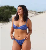 Conjunto de bikini azul con estampado a cuadros rosados. El corpiño es con aros y breteles ajustables, con gancho metálico en la espalda. La bombacha es tipo tanga con tiras laterales ajustables.