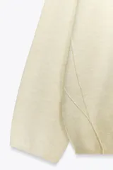 Jersey oversize de punto color crema, con cuello redondo y manga larga. Presenta costuras marcadas en los hombros y los laterales.