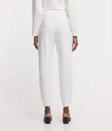 Conjunto de dos piezas color beige, compuesto por un sweater de manga larga con cuello polo y cierre frontal parcial, y un pantalón jogger a juego con cordón ajustable en la cintura.