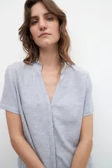 Blusa celeste de lino con cuello mao con volados, mangas cortas y cierre frontal con botones.
