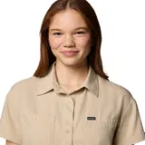 Camisa de manga corta Columbia, color beige, con cuello clásico, cierre frontal con botones y dos bolsillos frontales funcionales. Confeccionada con tecnología Omni-Shade para protección solar y Omni-Wick para absorción de humedad.