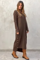 Vestido midi de punto color azul marino, con cuello en V, mangas largas y diseño holgado. Presenta un patrón de rombos en relieve y aberturas laterales con botones decorativos en el ruedo.