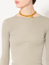 Remera de punto con textura suave, manga larga y escote redondo. Presenta un diseño ajustado al cuerpo con espalda abierta y largo a la primera cadera.