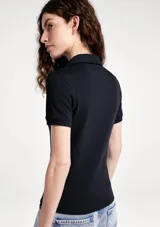 Remera polo de manga corta, color blanco, de corte ajustado con cuello camisero y cartera de tres botones frontales.