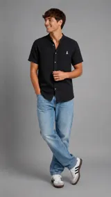 Camisa de manga corta color negro con cuello mao, cierre frontal de botones y bordado pequeño en el pecho.