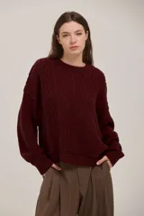 Sweater de punto con diseño de trenzas, cuello redondo y corte holgado. Presenta un estilo clásico con acabado en puños y ruedo acanalados.