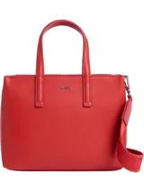 Cartera tote pequeña de piel sintética reciclada color rojo, con asas de mano fijas y correa ajustable opcional. Presenta cierre de cremallera superior, bolsillos interiores con ranura y logo metálico de Calvin Klein en el frente.
