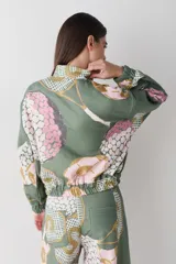 Campera bomber de corte holgado con cierre frontal, confeccionada en tela con estampado gráfico de pelotas de fútbol y redes en tonos verdes, rosados y ocres.