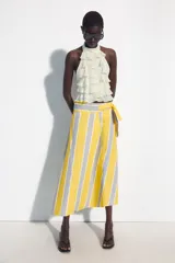Falda midi tipo pareo de tiro medio, confeccionada en algodón con diseño de rayas verticales en tonos amarillo, gris y blanco. Presenta un bajo asimétrico y cierre lateral con lazada.