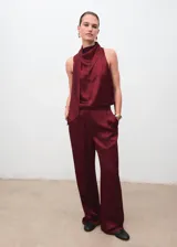 Blusa de satén color bordó con cuello drapeado y detalle de fular integrado que se sujeta en el hombro. Diseño sin mangas con tirantes anchos y corte recto.