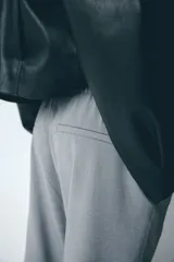 Pantalón de corte holgado color gris, con cintura elástica y cordón de ajuste trenzado en tonos rojo y blanco. Presenta piernas rectas y bolsillos laterales.