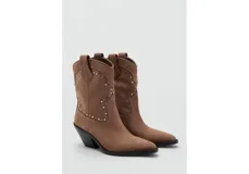 Botines de estilo texano en color marrón claro, confeccionados en piel bovina, con diseño de caña baja, puntera fina y detalles de tachas metálicas en la parte frontal y lateral.