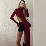 Top rojo con cuello alto, manga larga y diseño asimétrico con una abertura lateral pronunciada y cauda larga.