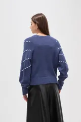 Sweater de punto color azul con diseño de fantasía en forma de líneas curvas punteadas en color celeste. Presenta cuello redondo a la base, mangas largas con puños acanalados y corte holgado.
