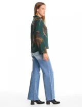 Camisa de crepe marca ABS Allen Schwartz, color marrón con estampado de hojas en tonos verdes y azules. Presenta cuello con solapa, cierre frontal con botones, mangas largas anchas y detalle de bordado con mostacillas en los hombros.