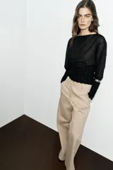 Jersey de punto semitransparente color crudo, con cuello redondo, manga larga y detalles elásticos de nido de abeja en el torso y en los puños.