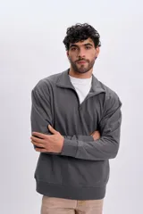 Buzo deportivo gris con cuello alto y cierre frontal parcial, de manga larga y diseño holgado.