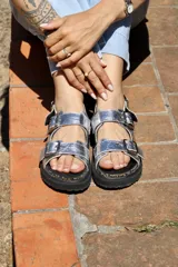 Sandalias plateadas con tiras anchas y hebillas metálicas, plataforma de goma negra y plantilla de corcho.