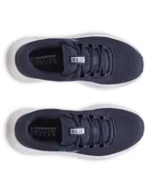 Championes de running Under Armour modelo Charged Surge 4, color azul marino con entresuela blanca y logo en celeste. Presentan parte superior de malla transpirable con refuerzos sintéticos, amortiguación Charged Cushioning en la entresuela y suela de goma resistente.