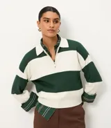 Suéter de punto color verde oscuro y blanco, con cuello polo, cierre frontal parcial de cremallera metálica y mangas largas con puños. Presenta un estampado de rayas horizontales.